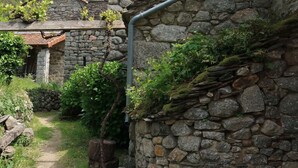 Ein Steinhaus mit rustikaler Steinwand und einer Metallrohrleitung.