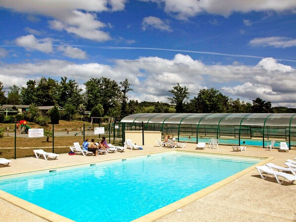 Ein Swimmingpool mit Liegestühlen und einem überdachten Bereich.