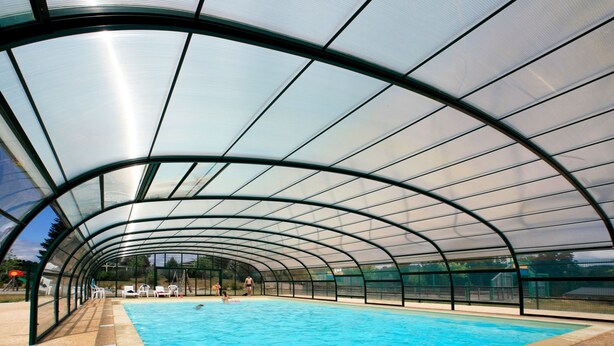 Una piscina techada con una estructura de techo curva.