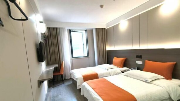 A hotel room with two beds, a desk, a chair, a window, and a television. - Lake Holiday Hotel (Chizhou)
