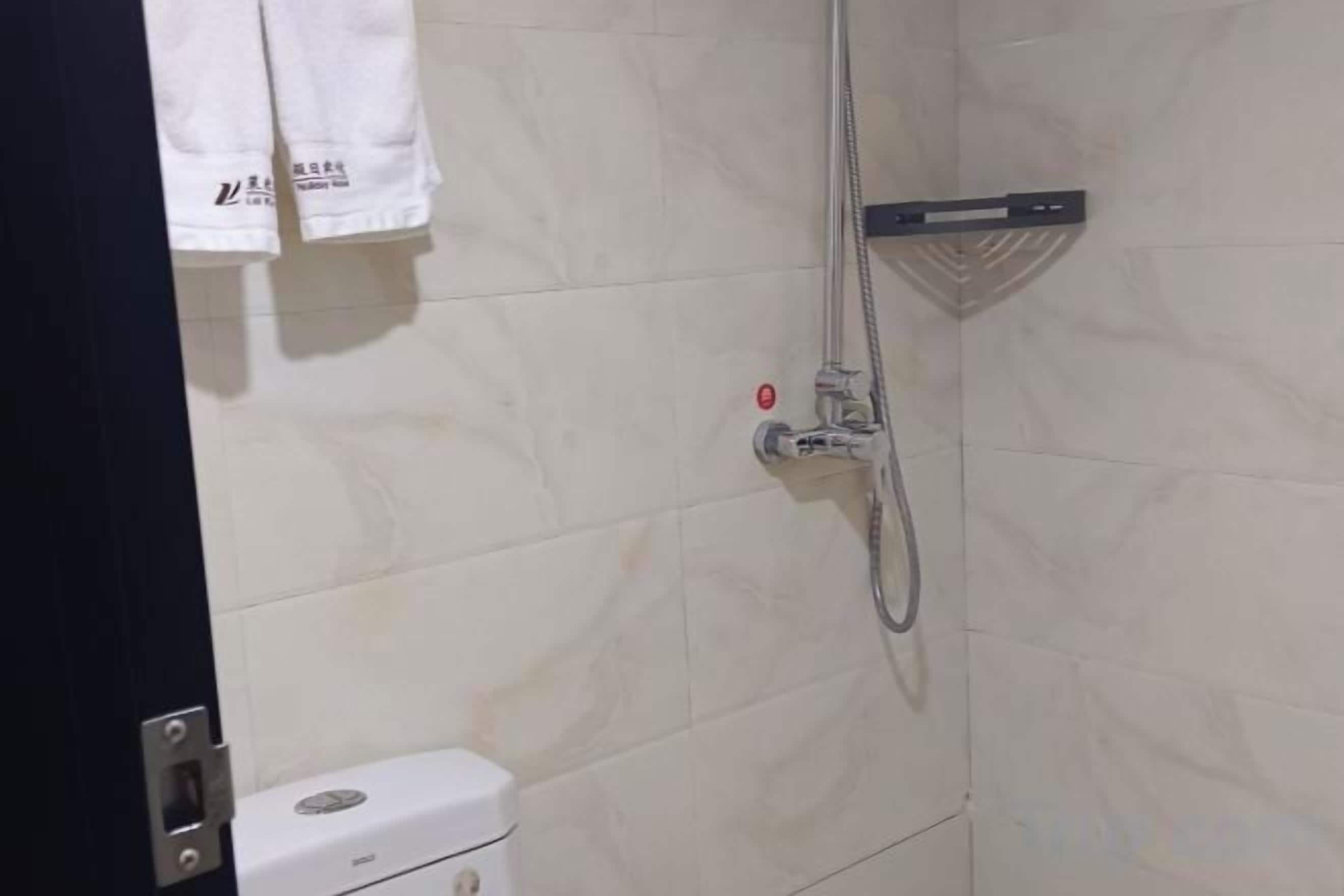 A bathroom with a shower, a toilet, and a towel rack.