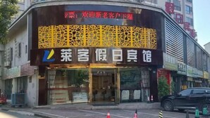 A hotel with a prominent sign featuring a geometric pattern and the name "菜客假日馆". - Lake Holiday Hotel (Chizhou)
