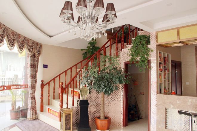 A staircase with a wooden handrail, a chandelier, and potted plants.