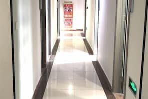 A hotel corridor with a tiled floor, a red informational sign, and an elevator control panel. - Lake Holiday Hotel (Chizhou)