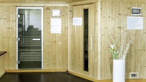 A wooden interior with a staircase, a white vase with plants, and informational signs. - Les Jardins Renaissance by Interhome (Azay-le-Rideau)