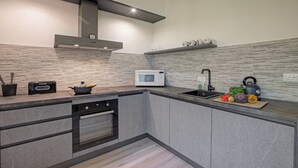 A modern kitchen with a microwave, toaster, and kettle on the counter, a sink, and a stove. - Porto Letizia Napoli 8, Porlezza, Italy (Porlezza)