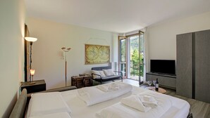 A hotel room with a large bed, a sofa, a TV, and a balcony with a view. - Porto Letizia Napoli 8, Porlezza, Italy (Porlezza)
