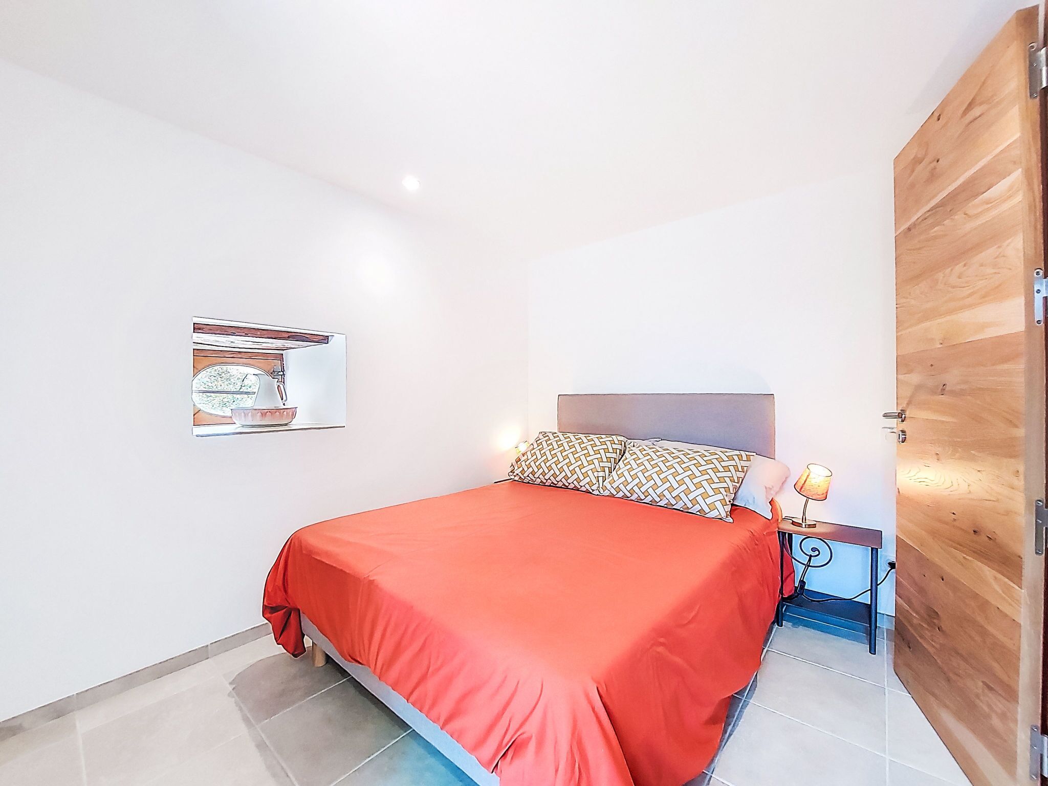 Une chambre à coucher avec un lit, une table de chevet, une lampe et une porte en bois.