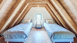 A bedroom with two beds, wooden beams, a window, and a nightstand. - Vacation home Cuzac by Interhome (Labastide-Murat)