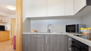 Une cuisine moderne avec des meubles gris, un évier en acier inoxydable, un four à micro-ondes et un four traditionnel.