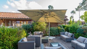 An outdoor patio area with wicker furniture and a large umbrella.