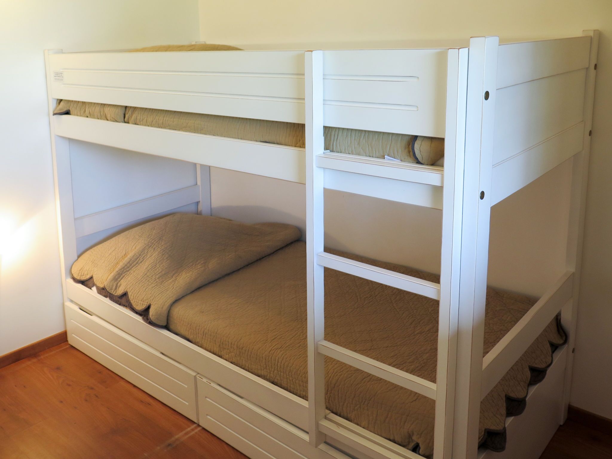A bunk bed with a lower bunk and a top bunk, both with storage drawers and a headboard.