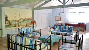 Una habitación con mobiliario tapizado a rayas, un cuadro de una escena costera y suelo de madera.