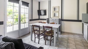 Una cocina moderna con una mesa de comedor, sillas, un televisor y un ventanal grande.