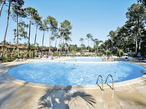 Una gran piscina al aire libre rodeada de palmeras y sillas de descanso.