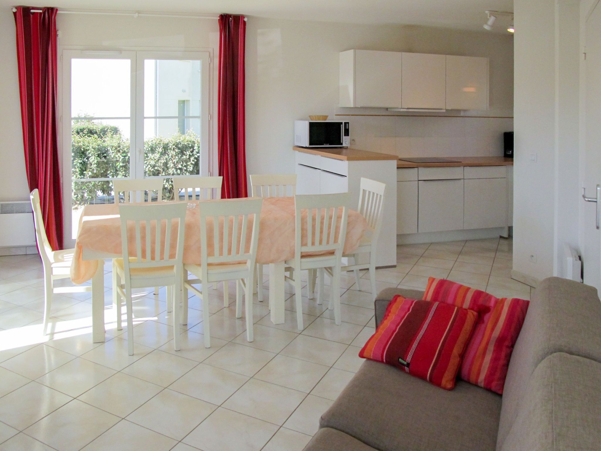 Un soggiorno luminoso con zona pranzo, cucina e vista su spazi verdi.