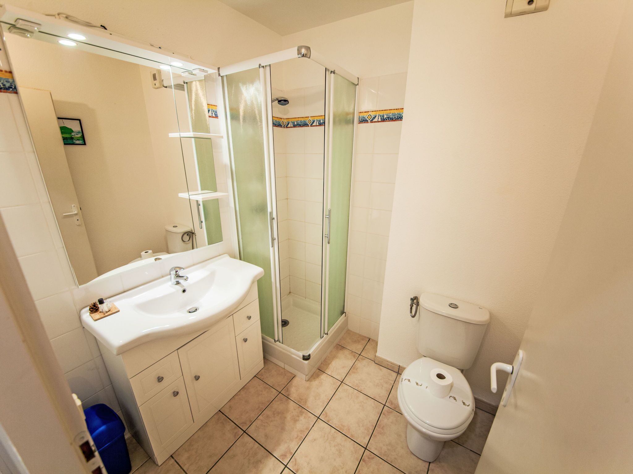 A bathroom with a glass-enclosed shower, a sink with a mirror, and a toilet.
