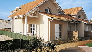 A two-story house with a sloped roof, a covered porch, and a fenced yard. - Résidence Dune Blanche - Océan1 by Interhome (Biscarrosse)