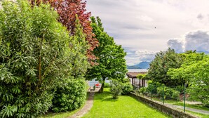 A lush garden with a pathway leading to a gazebo overlooking a lake.