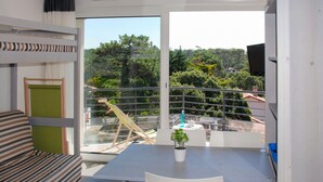 A balcony with a table, chairs, a potted plant, and a view of a forested area. - Résidence Plage Centrale T2 by Interhome (Hossegor)