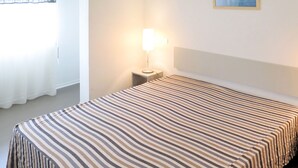 A hotel room with a bed, a nightstand, a lamp, and a painting on the wall. - Résidence Plage Centrale T2 by Interhome (Hossegor)