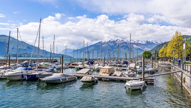 Ein Yachthafen mit vertäuten Booten, einer Anlegestelle und einer Bergkulisse.