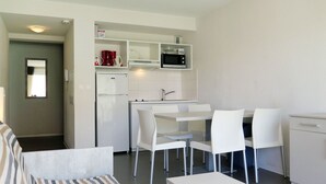 Un espacio habitable compacto con kitchenette, comedor y sofá.