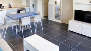 Een moderne keuken met een eethoek, een flatscreen televisie en een bank.