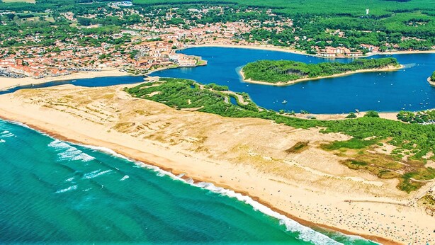 Luchtbeeld van een kustplaatsje met een strand, een jachthaven en woonwijken.