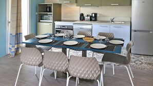 Uma cozinha moderna com uma mesa de jantar posta para quatro pessoas, equipada com cafeteira, torradeira e frigorífico.