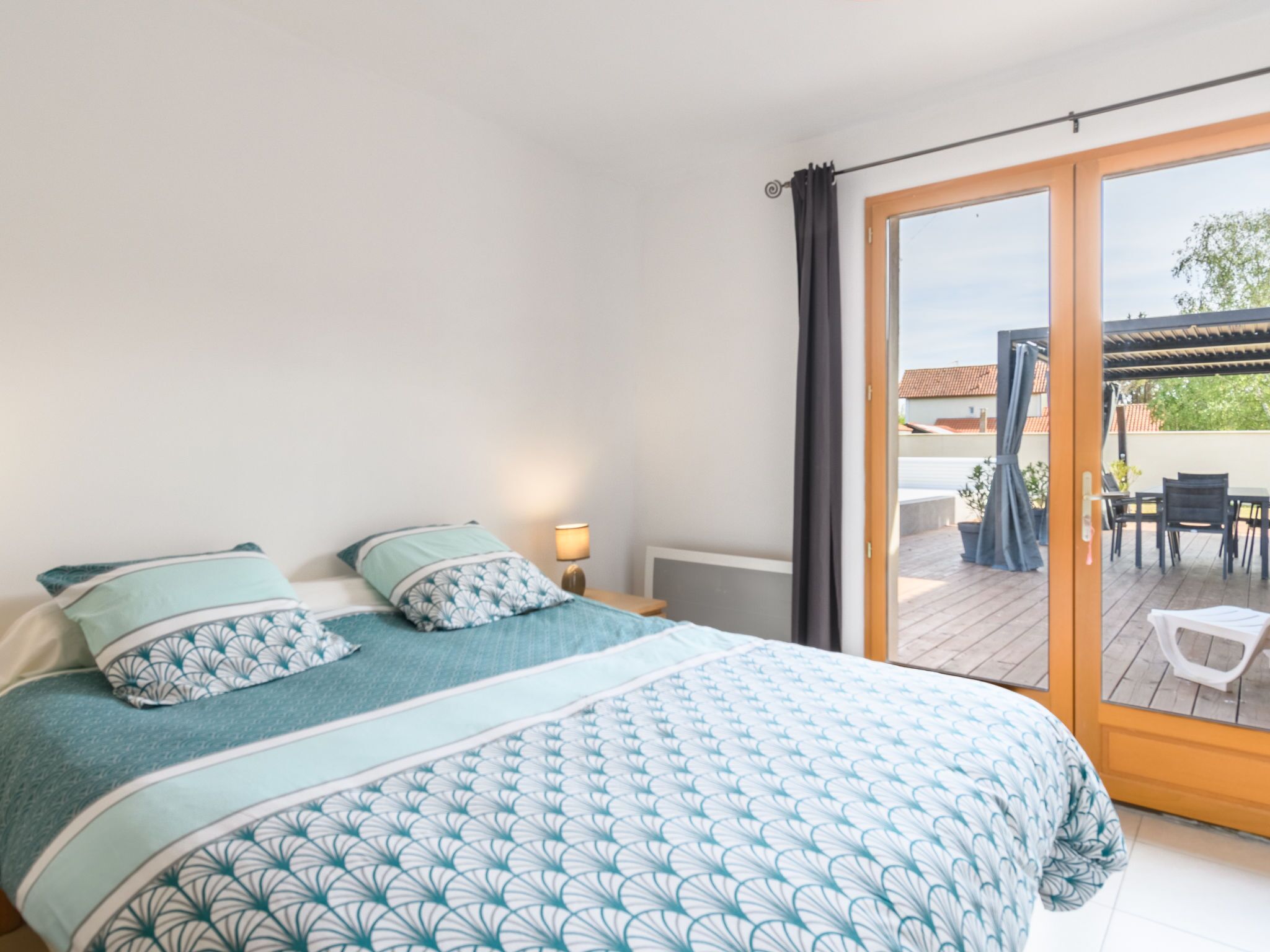 A bedroom with a bed, a nightstand, a lamp, and a sliding glass door leading to an outdoor patio.