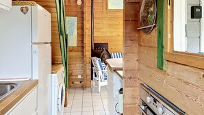 A compact kitchen with a refrigerator, washing machine, and a dining area with a table and chairs. - L'Escouarte by Interhome (Maubuisson)
