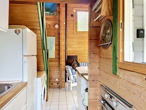 Une cuisine compacte équipée d’un réfrigérateur, d’un lave-linge et d’un coin repas avec une table et des chaises.