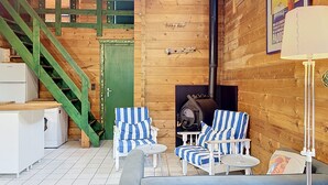 A wooden interior with a staircase, a fireplace, striped chairs, a sofa, and a small table. - L'Escouarte by Interhome (Maubuisson)