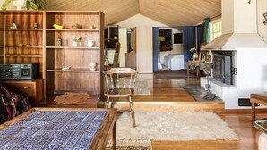 Ein geräumiger Loft mit hohen Decken, Holzboden und einer gemütlichen Sitzecke mit einem gemusterten Teppich und einem Sessel.
