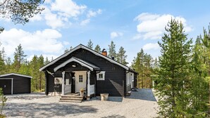 En hytte med veranda, en dør og et lille tilbyggeskur.