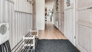En gang med hvide panelvægge, en sort måtte og en hvid radiator.