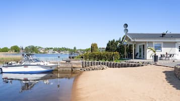 A sandy beach with a boat docked near a house with a satellite dish.