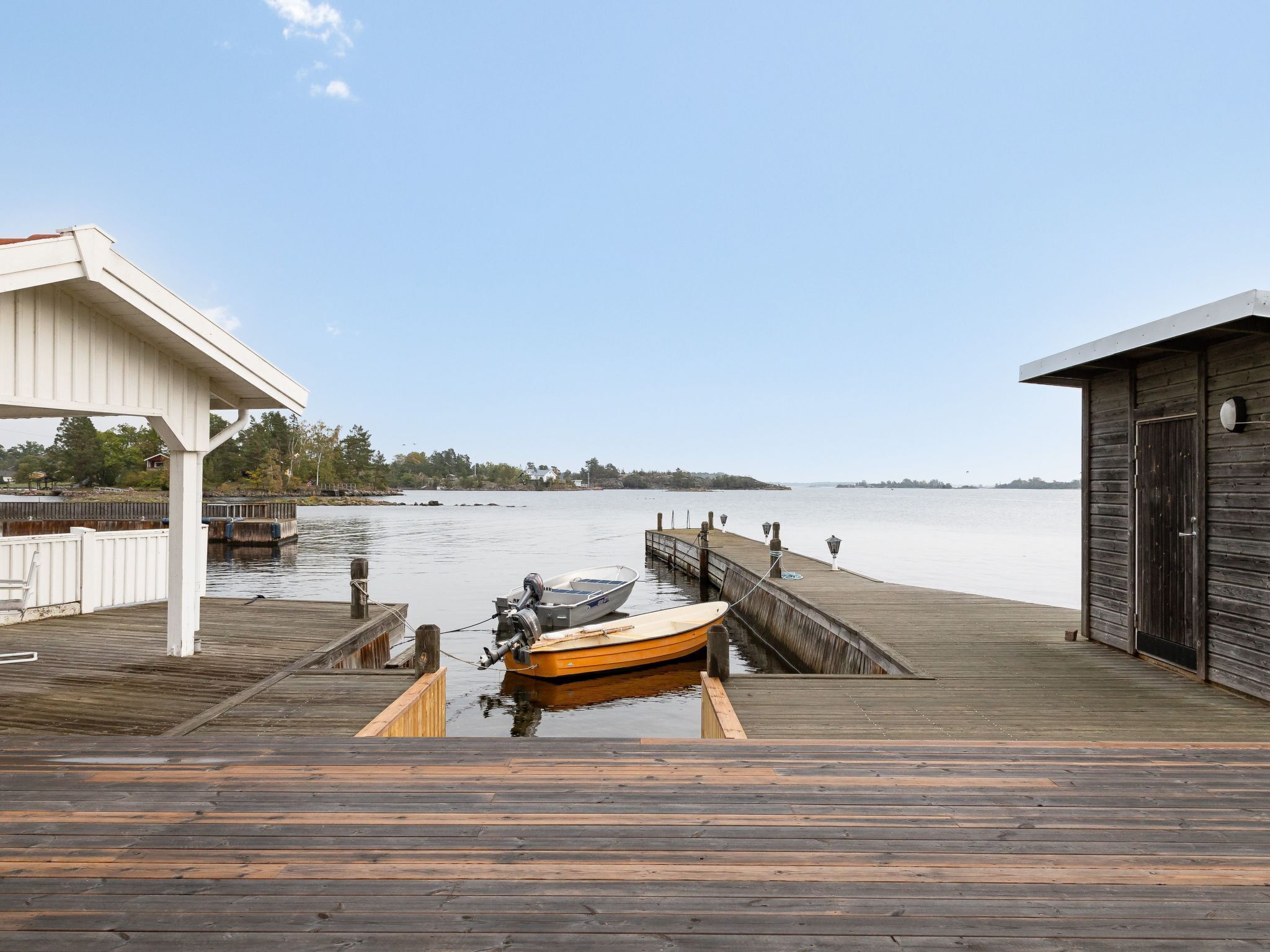 A wooden dock leading to a calm lake with a boat moored at the end.