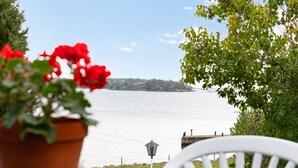 Une vue sur un lac, avec une chaise et un pot de fleurs au premier plan.