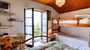 Una habitación acogedora con una cama nido, un escritorio con silla, un televisor y una ventana con cortinas.