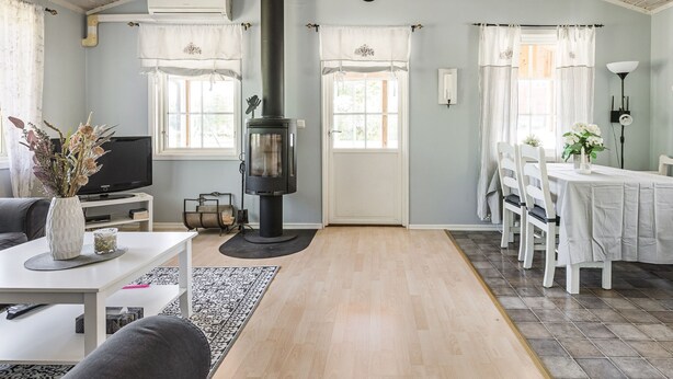 A cozy living room with a fireplace, a television, and a dining area with a table and chairs. - Skärvudde Huset by Interhome (Kalvsvik)