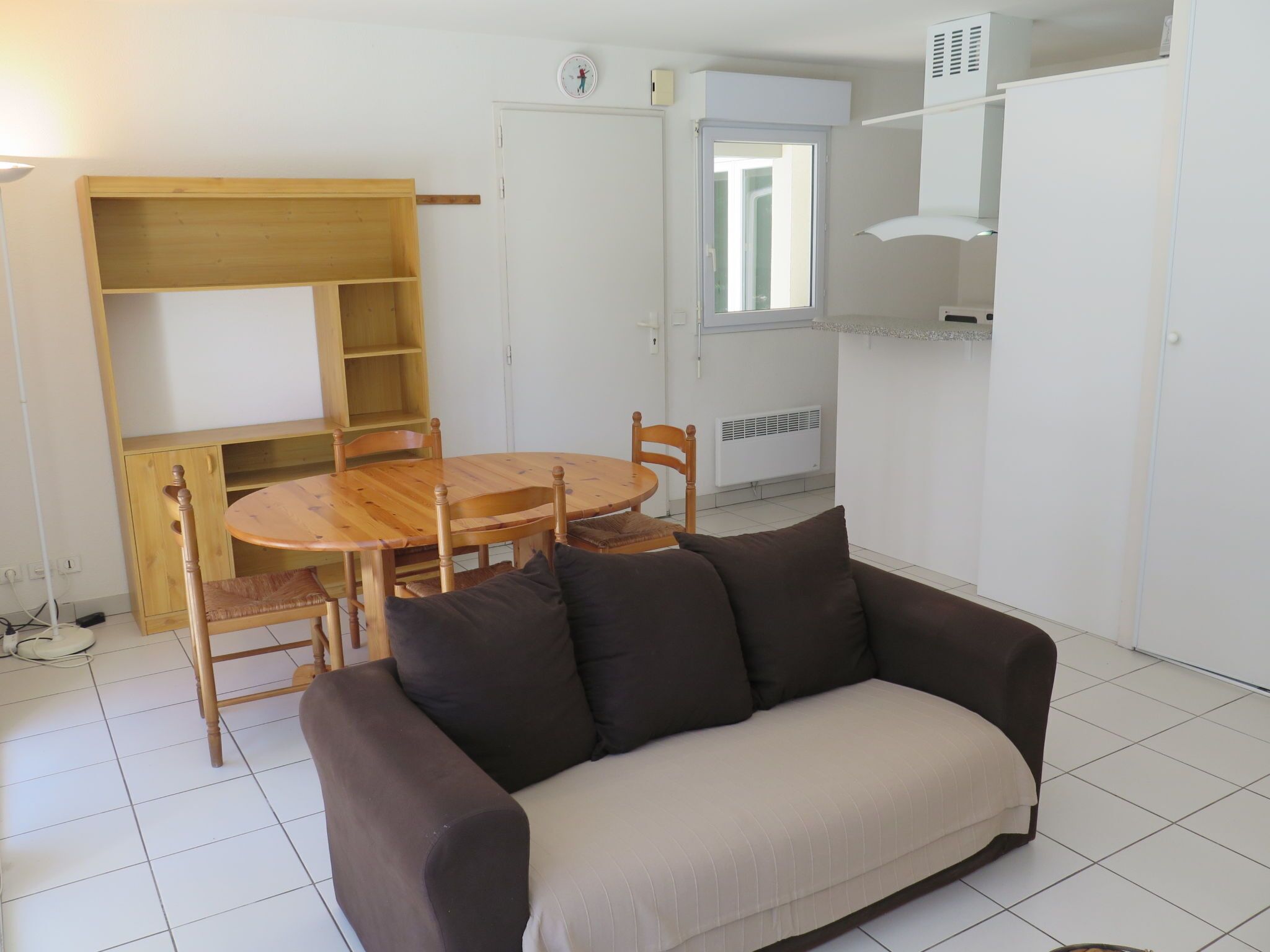 Une petite pièce bien éclairée, avec une table et des chaises en bois, un canapé, une étagère intégrée et une fenêtre donnant sur un beau paysage.