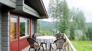 A wooden deck with a table and chairs, overlooking a lake and forest. - Borrsjön by Interhome (Gräsmark)