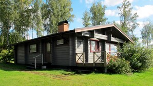 A rustic cabin with a chimney, large windows, and a porch. - Borrsjön by Interhome (Gräsmark)