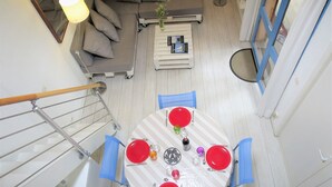 A dining area with a round table set for four, a grey sofa, a small coffee table, and a staircase with a railing.
