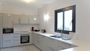 A modern kitchen with white cabinets, a built-in oven, a sink, and a window above the sink. - Vacation home Yara by Interhome (Lacanau)