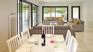 A dining area with a table set for four, a bottle of wine, and a bicycle in the background. - Vacation home Yara by Interhome (Lacanau)
