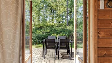 An open wooden door leading to an outdoor deck with a table and chairs.