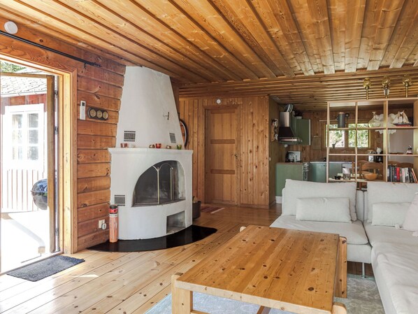A cozy cabin interior with a fireplace, wooden walls, a sofa, and a dining table.